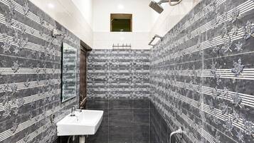 A bathroom with a white sink, a mirror, a shower, and a toilet.