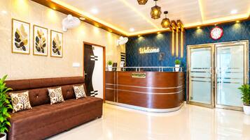 A reception area with a brown sofa, a reception desk, a clock, and framed artwork on the wall.