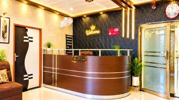 A reception desk with a 'RECEPTION' sign, a 'Welcome' sign, a clock, and a check-in counter.