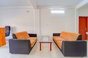 Una sala moderna con dos sofás, una mesa de centro de vidrio y una puerta.