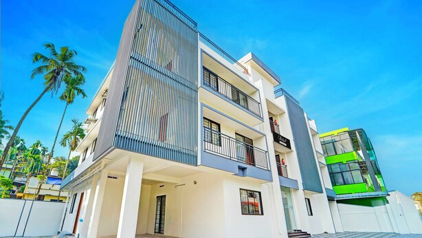 Un immeuble moderne à plusieurs étages, doté de balcons, d’un toit plat et d’un motif de sol à carreaux.