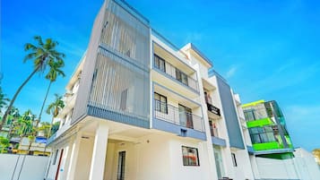 Un edificio moderno de varios pisos con balcones, techo plano y patrón de piso a cuadros.