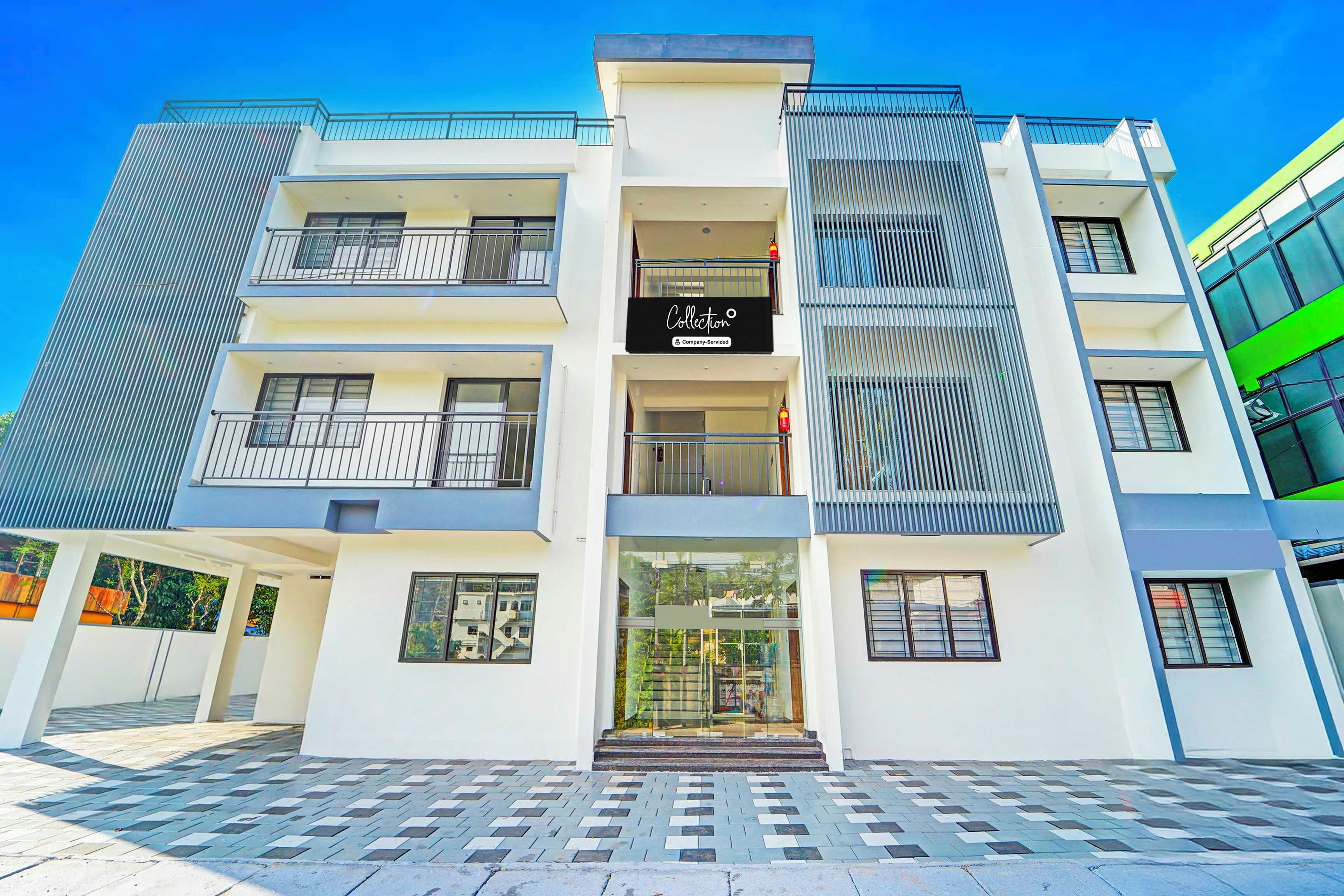 A modern multi-story building with a central entrance, balconies, and a sign indicating a company-serviced collection.