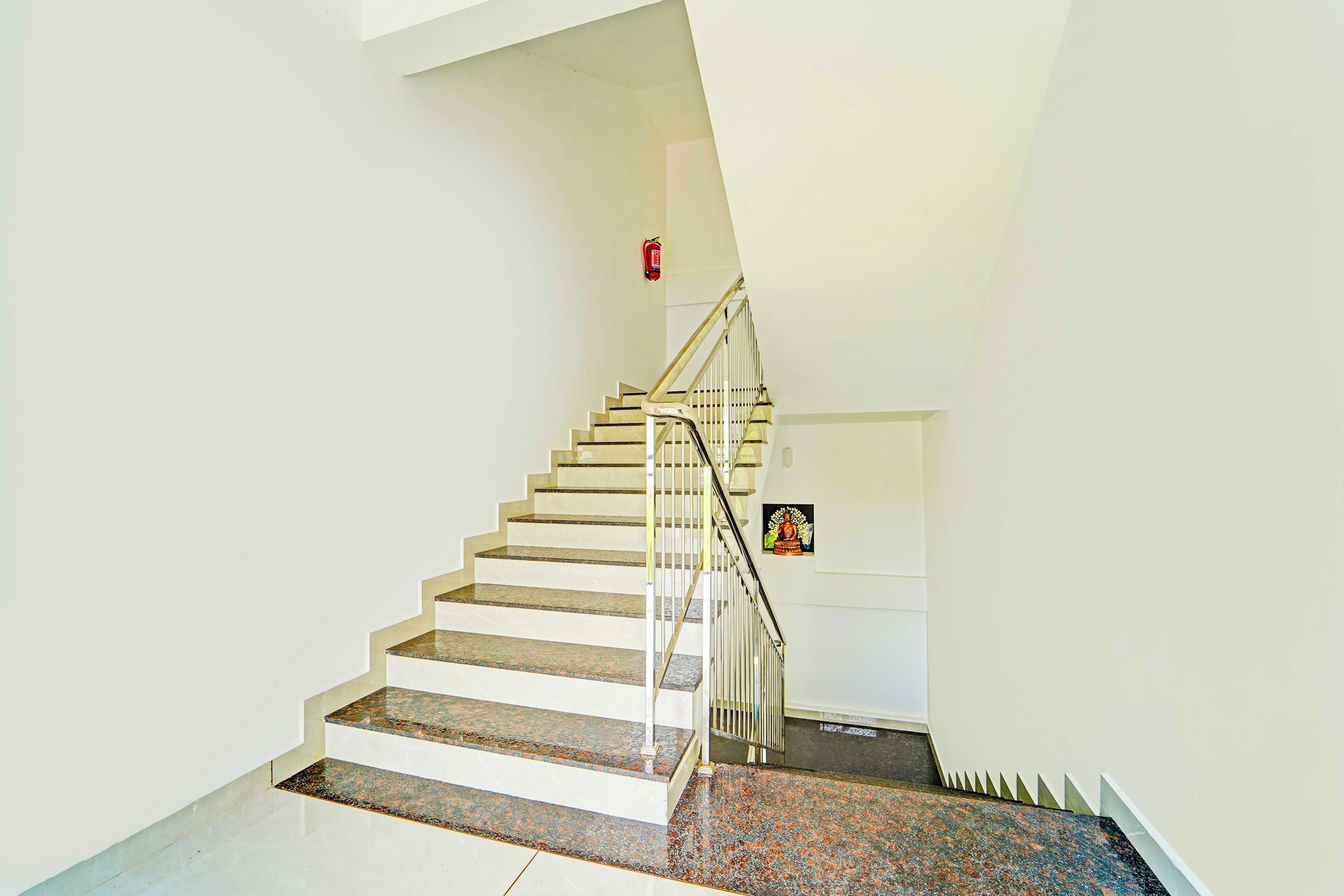 A staircase with a handrail, a fire extinguisher on the wall, and a statue.