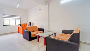 Una habitación de hotel moderna con un sofá, una mesita y una recepción.
