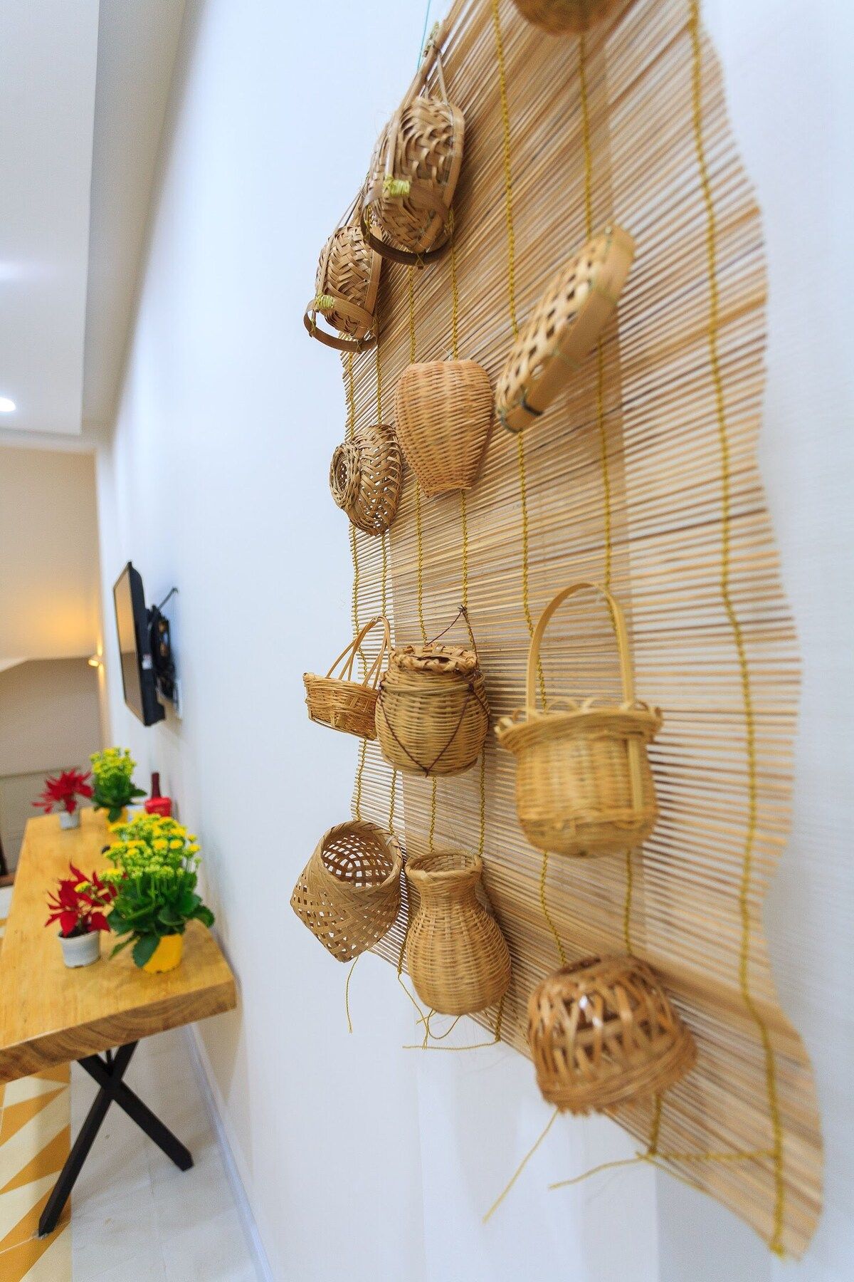 A wall with woven baskets and a table with potted plants.