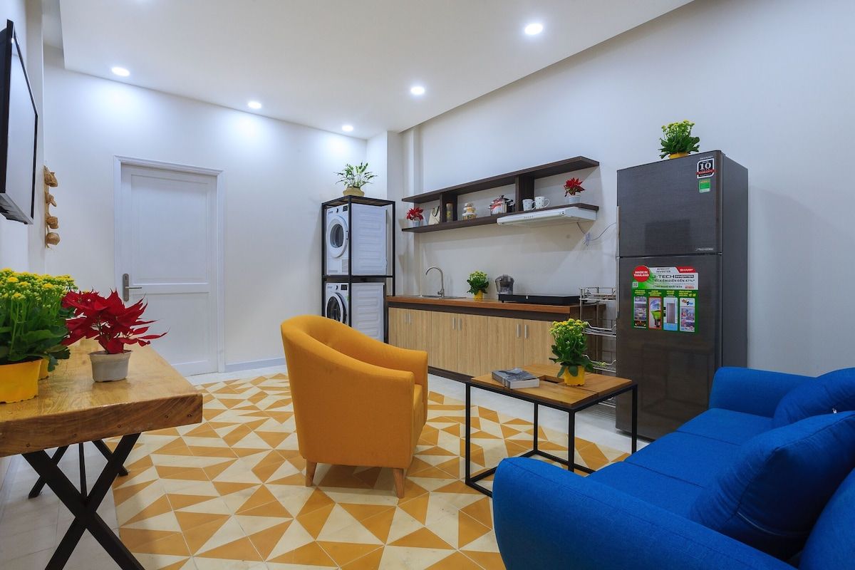 A modern kitchen with a refrigerator, a washing machine, and a dining area with a table and chairs.
