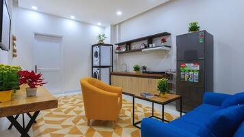 A modern kitchen with a refrigerator, a washing machine, and a dining area with a table and chairs.