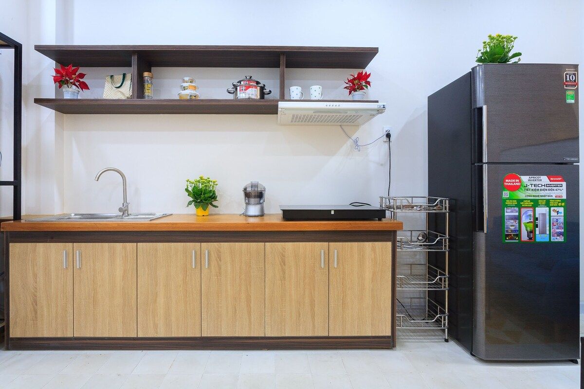 A kitchen with wooden cabinets, a stainless steel refrigerator, and a shelf with kitchen items.