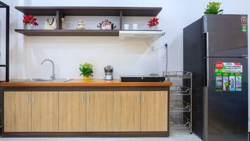 A kitchen with wooden cabinets, a stainless steel refrigerator, and a shelf with kitchen items.
