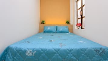 A bedroom with a bed, a window with a view, and a wall with a light fixture.