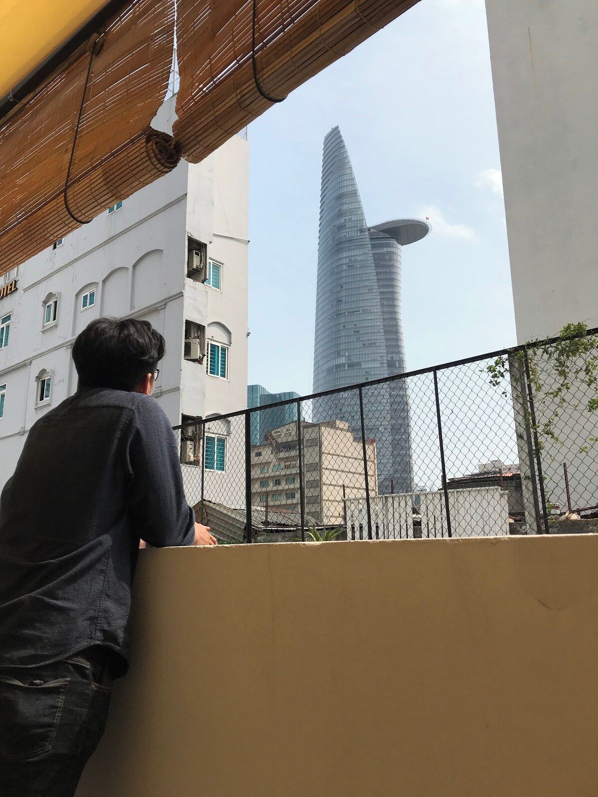 Una persona in piedi su un balcone con vista su un grattacielo moderno dal design originale.