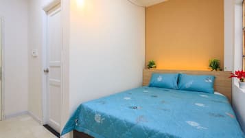 A bedroom with a bed, a door, and a wall-mounted light fixture.
