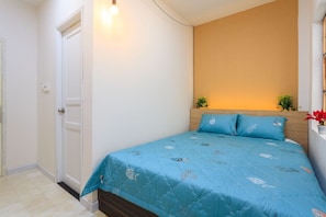 Une chambre à coucher avec un lit, une porte et un luminaire fixé au mur.