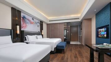 Habitación de hotel con dos camas, un escritorio, un televisor y un cuadro abstracto grande en la pared.