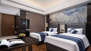 Habitación de hotel con dos camas, un escritorio de madera, un espejo y un mural decorativo en la pared.