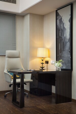 Une chambre d’hôtel équipée d’un bureau, d’une chaise, d’une lampe et d’un tableau encadré au mur.