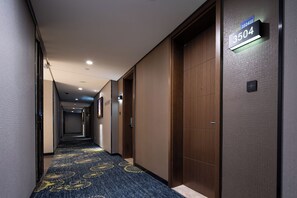 A hotel hallway with a carpeted floor, wooden doors, and a sign indicating room number 3504.