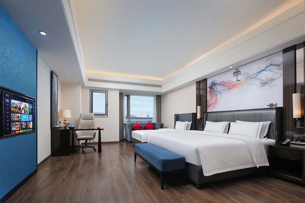 Una habitación de hotel moderna con una cama grande, un escritorio y vistas a la ciudad.