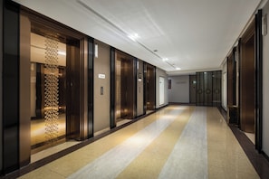 A hotel corridor with multiple elevators, a patterned glass wall, and a tiled floor. - Jiaruide Hotel IFS Changsha (Changsha)