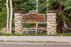 A wooden sign with the text 'SAW MILL INN' surrounded by a stone wall. - RidgeView Retreat | Steps to Hideaway Park & Town (Winter Park)