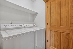 A laundry area with two white dryers and a wooden door. - RidgeView Retreat | Steps to Hideaway Park & Town (Winter Park)