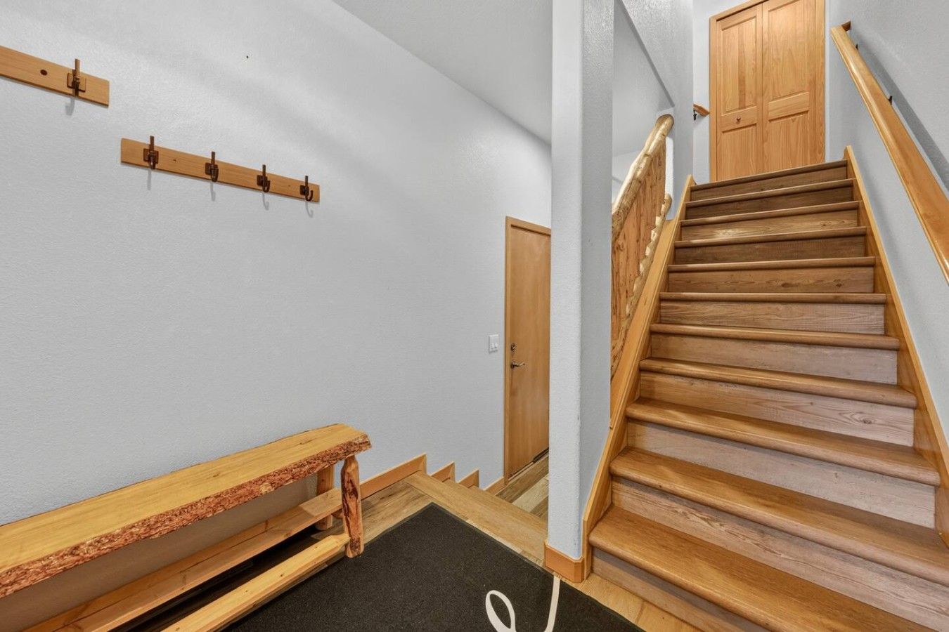 A staircase with wooden steps and a handrail, leading to a wooden door.