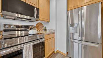 A modern kitchen with stainless steel appliances, wooden cabinets, and a granite countertop.