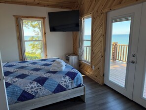 A bedroom with a bed, a TV, a window, and a door leading to a balcony. - 3-bedroom cabin centrally located between Geneva on the lake  & Ashtabula Harbor (Ashtabula)