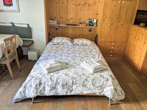 Ein Schlafzimmer mit einem Bett, einem Schreibtisch, einem Stuhl und einem Holzschrank.