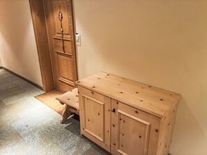 Ein Holzschrank mit Schubladen und eine Bank in einem Flur mit Teppichboden.