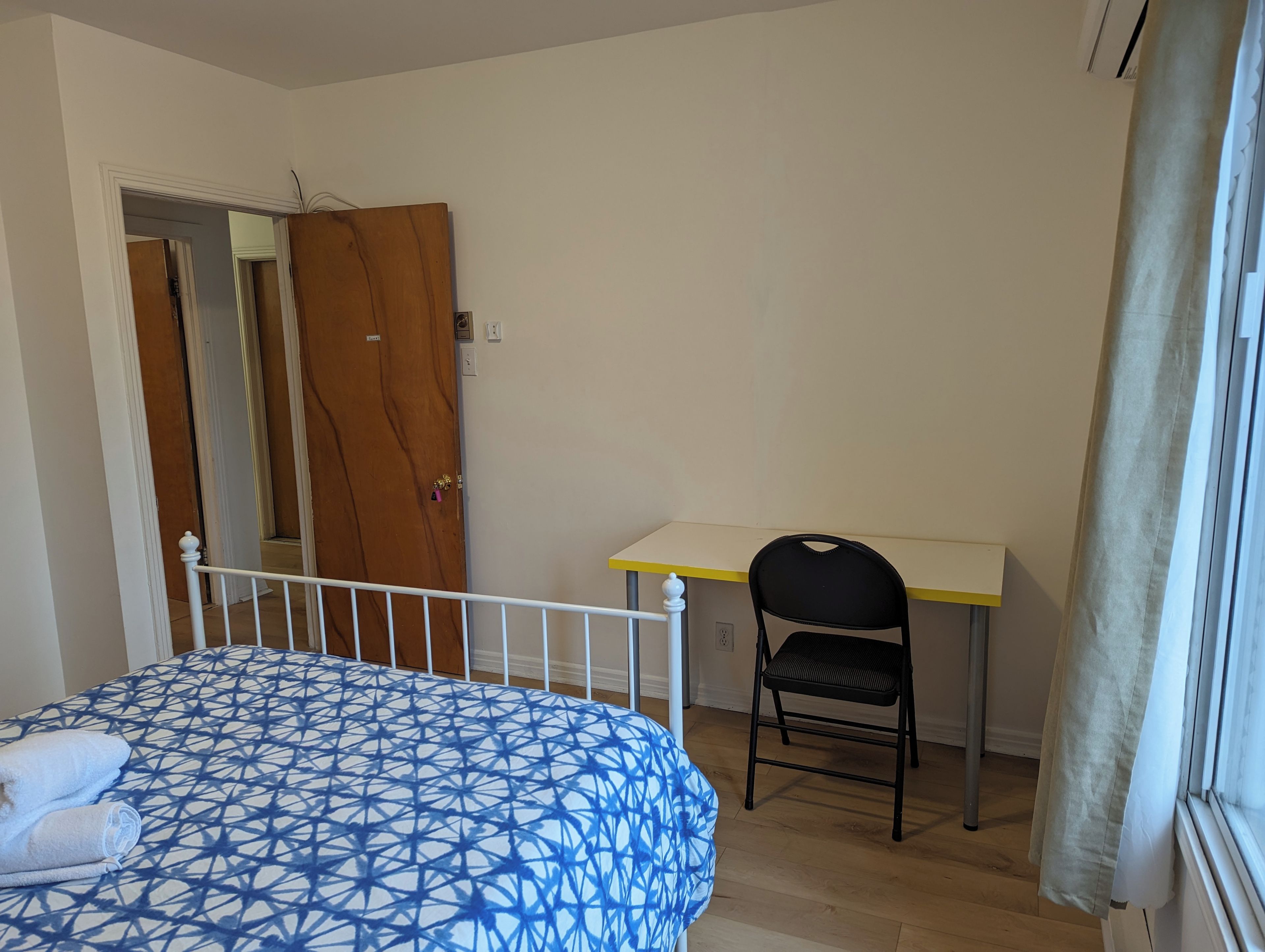 A bedroom with a bed, a desk, and a chair.
