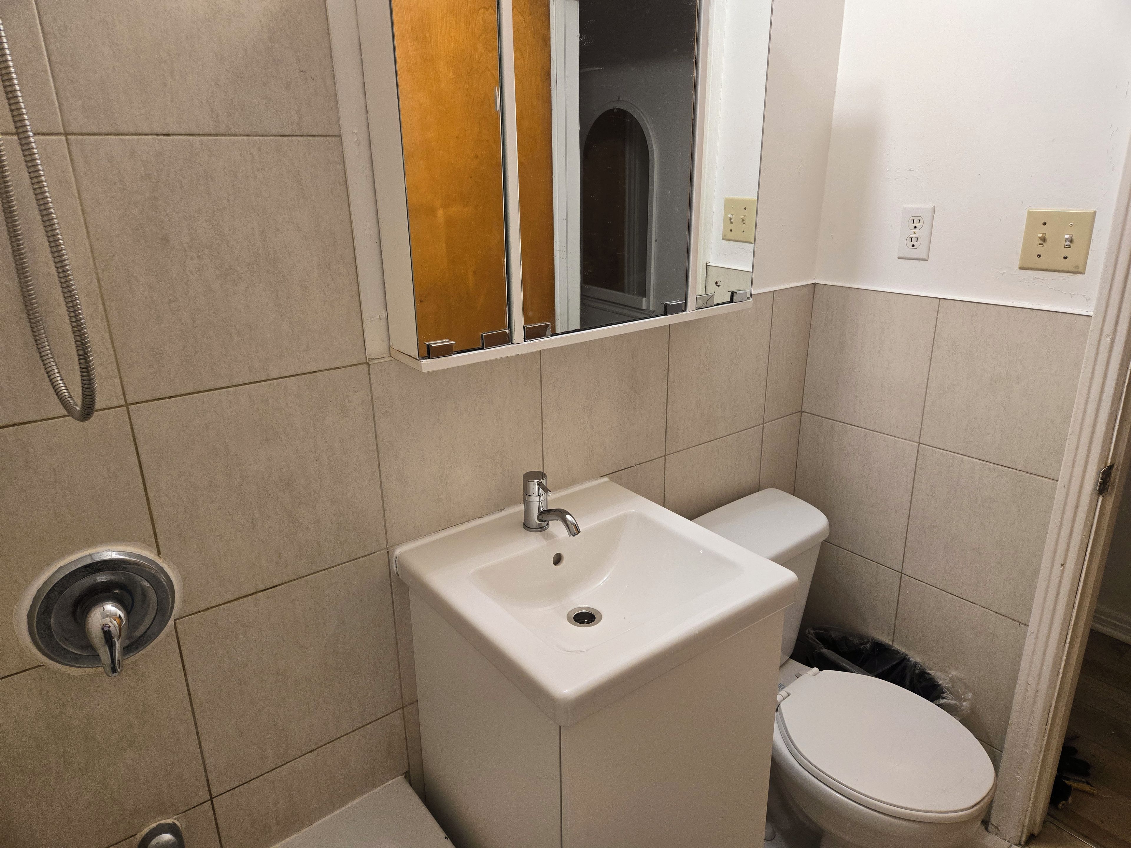 A bathroom with a white sink, toilet, and a shower area.