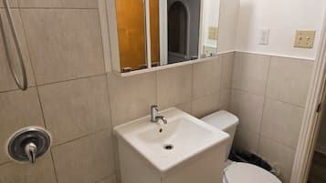 A bathroom with a white sink, toilet, and a shower area.