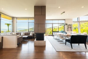Een ruime woonkamer met een groot raam, een eettafel en een bank.