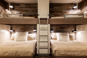 Een slaapkamer met een stapelbed, een centrale ladder, twee bedlampjes en een houten wand.