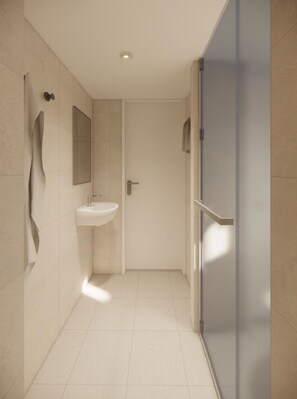 Un bany modern amb un rentapeus blanc, un mirall i una porta que condueix a una altra habitació.