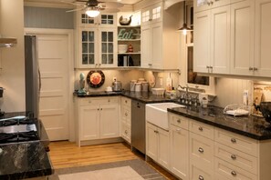 A kitchen with white cabinets, a black countertop, and a wooden floor. - The Lakefront Muskoka Detour (Gravenhurst)