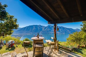 Un área de estar rústica al aire libre con vista a un lago y montañas.