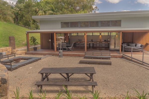 A modern house with a covered patio area, outdoor seating, and a barbecue grill.