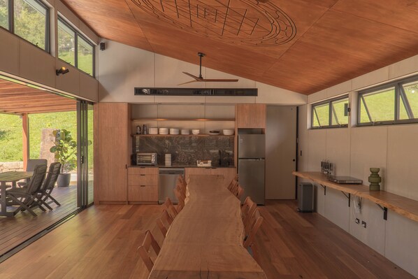 A modern kitchen with a central island, wooden flooring, and large windows.