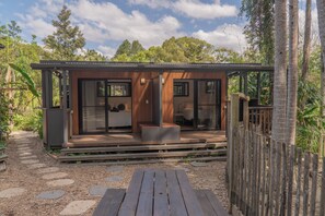 A modern cabin with a wooden exterior, large glass windows, and a deck area.
