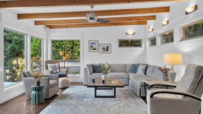 A spacious living room with a high ceiling, large windows, and a view of greenery outside. - The Grey Piper by Avantstay Ocean Views + Fire Pit + BBQ Walk to Beach (Arch Cape)