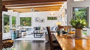 A spacious living room with a wooden ceiling, large windows, and a cozy seating area with a coffee table. - The Grey Piper by Avantstay Ocean Views + Fire Pit + BBQ Walk to Beach (Arch Cape)