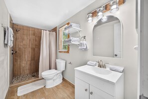 Une salle de bain moderne équipée d’une douche, de toilettes, d’un lavabo et d’un miroir.