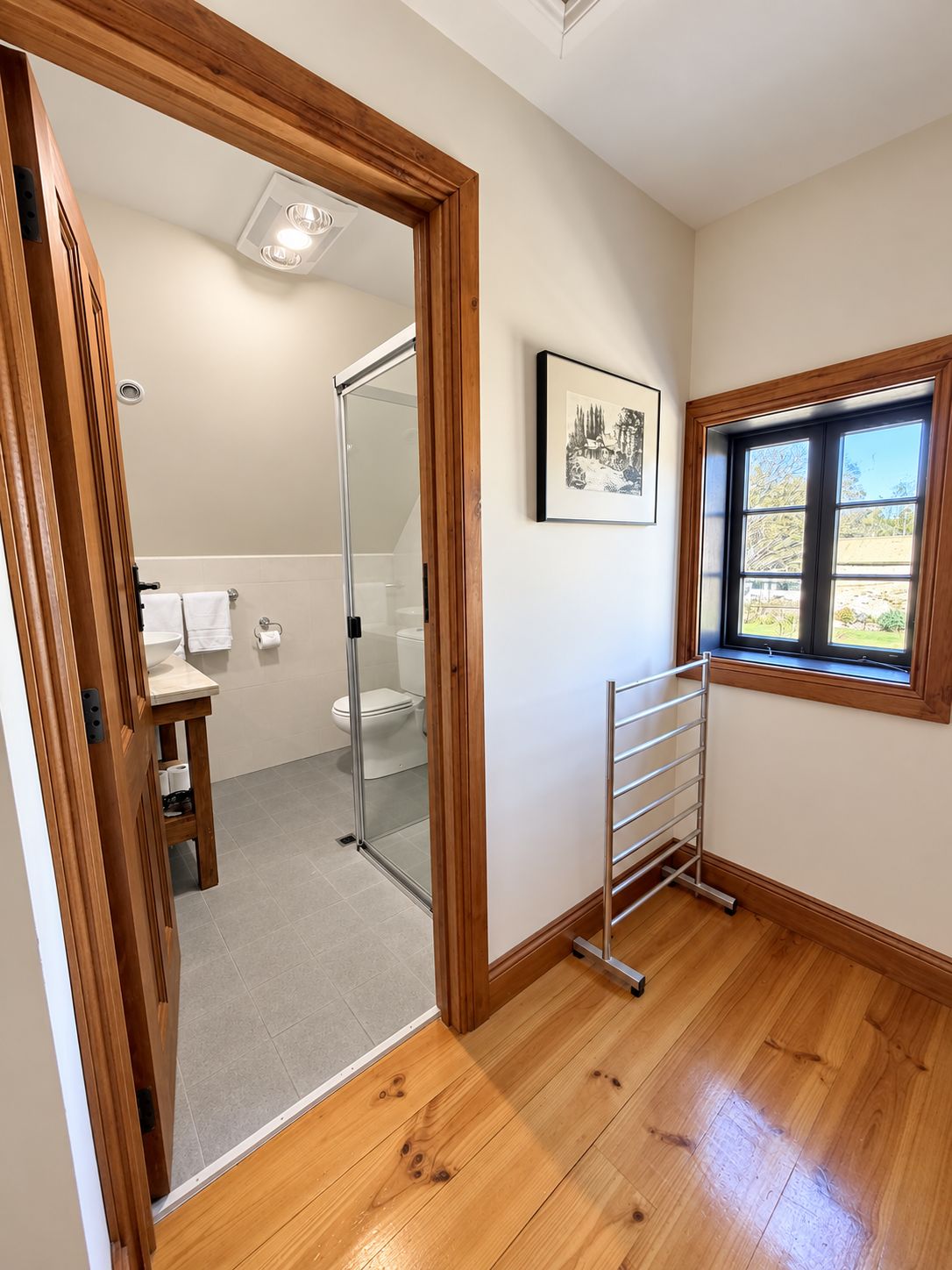 A bathroom with a glass shower door, a toilet, and a towel rack.