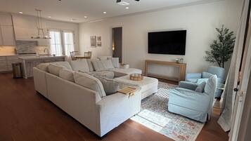 A modern living room with a sectional sofa, a TV, and a ceiling fan.