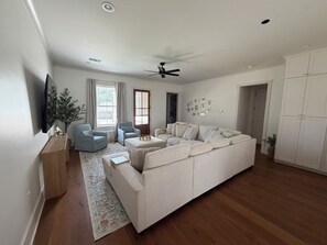 A modern living room with a sofa, chairs, a coffee table, and a television. - Entire Home, 3 King Beds, Sleeps 8, Near Ole Miss (Oxford)