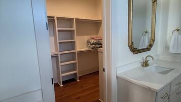 A bathroom with a white vanity, a mirror with a gold frame, and a wooden floor.