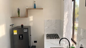 Une cuisine de taille réduite équipée d’un réfrigérateur, d’un évier et d’une cuisinière.